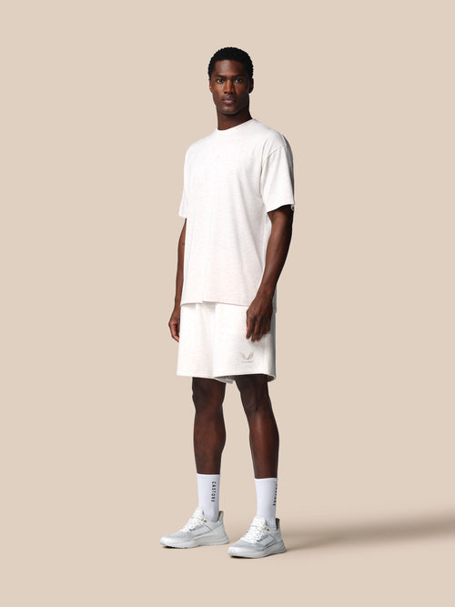 Man wearing a white t-shirt and shorts on a beige background