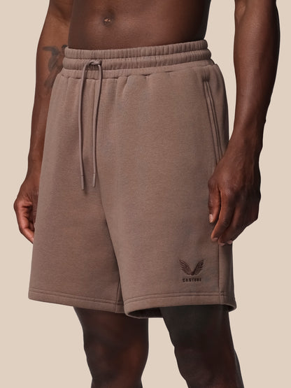 Brown shorts worn by a person on a beige background