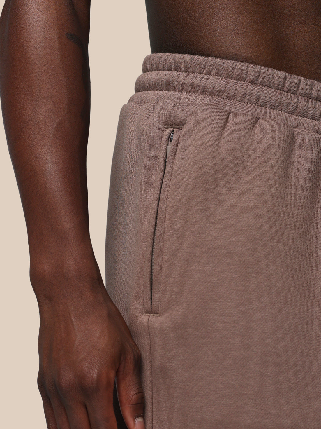 Brown sweatpants with a zipper on a beige background