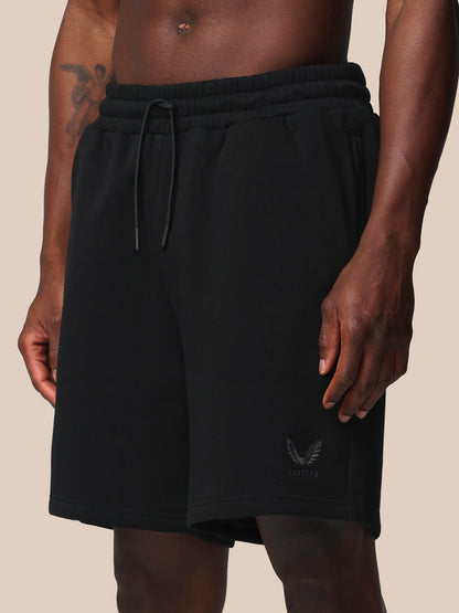 Black shorts with a brand logo on a beige background