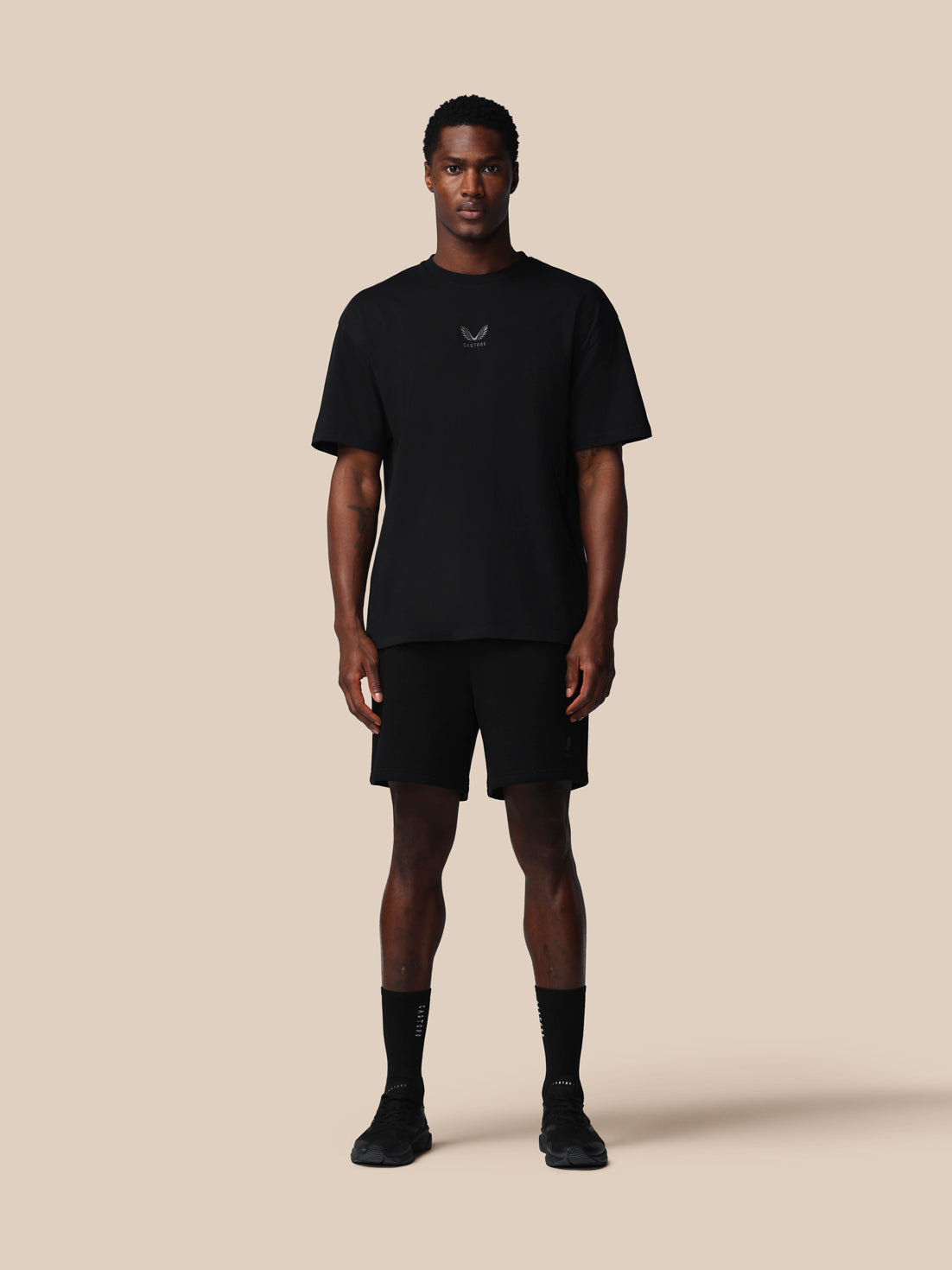 Man wearing a black t-shirt and shorts set on a beige background