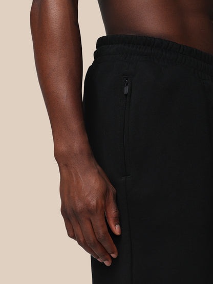 Black pants worn by a person on a beige background