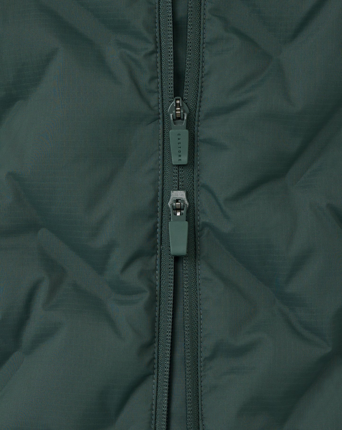 Close-up of a green jacket zipper on a textured fabric background