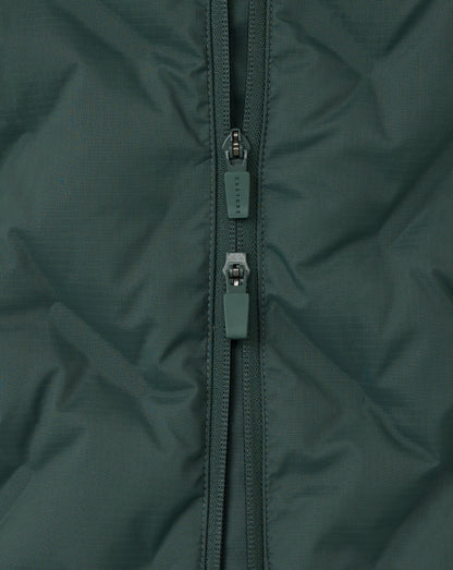 Close-up of a green jacket zipper on a textured fabric background