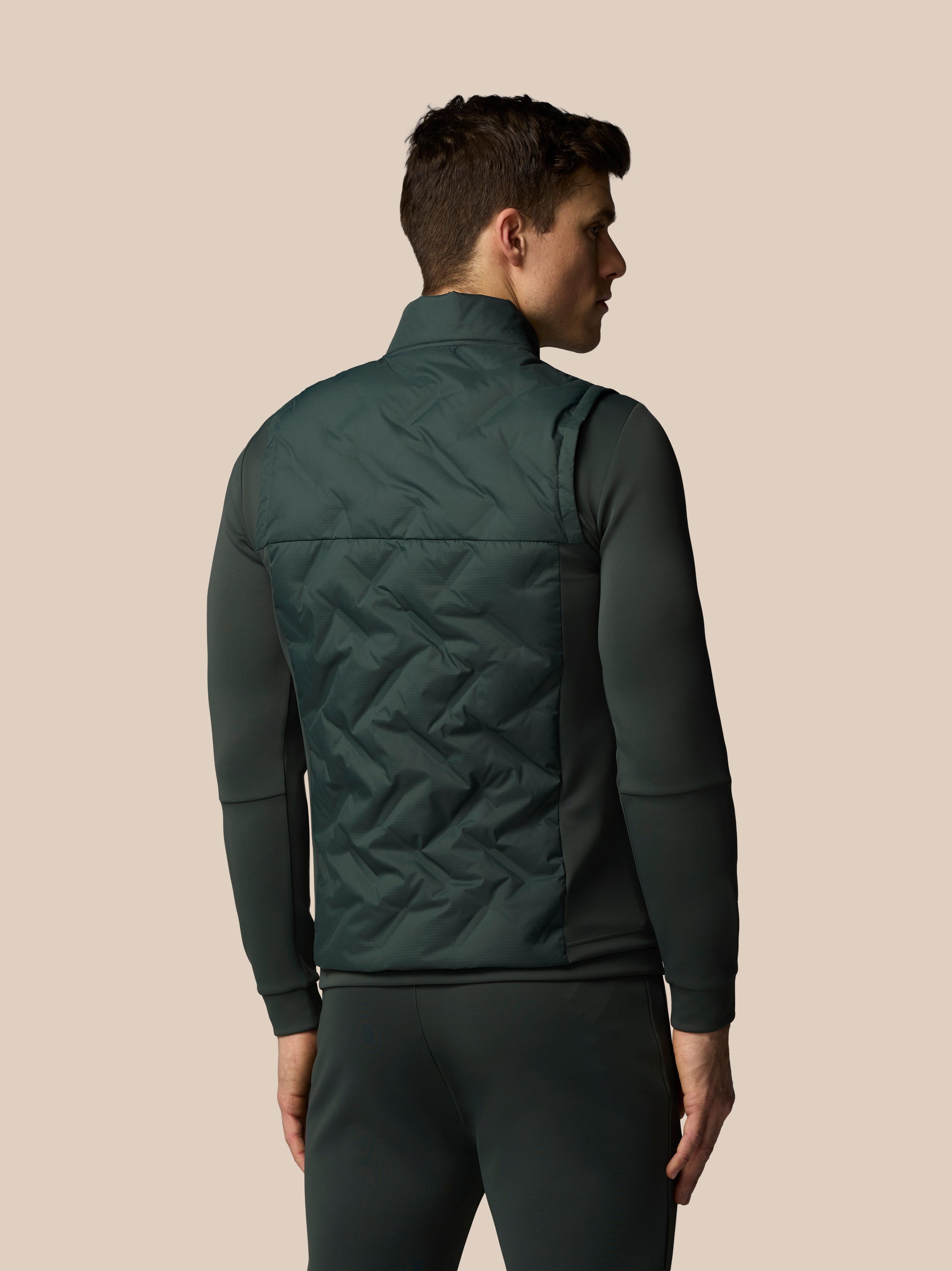 Man wearing a green quilted vest on a beige background
