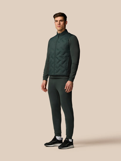 Man wearing a dark green tracksuit on a beige background