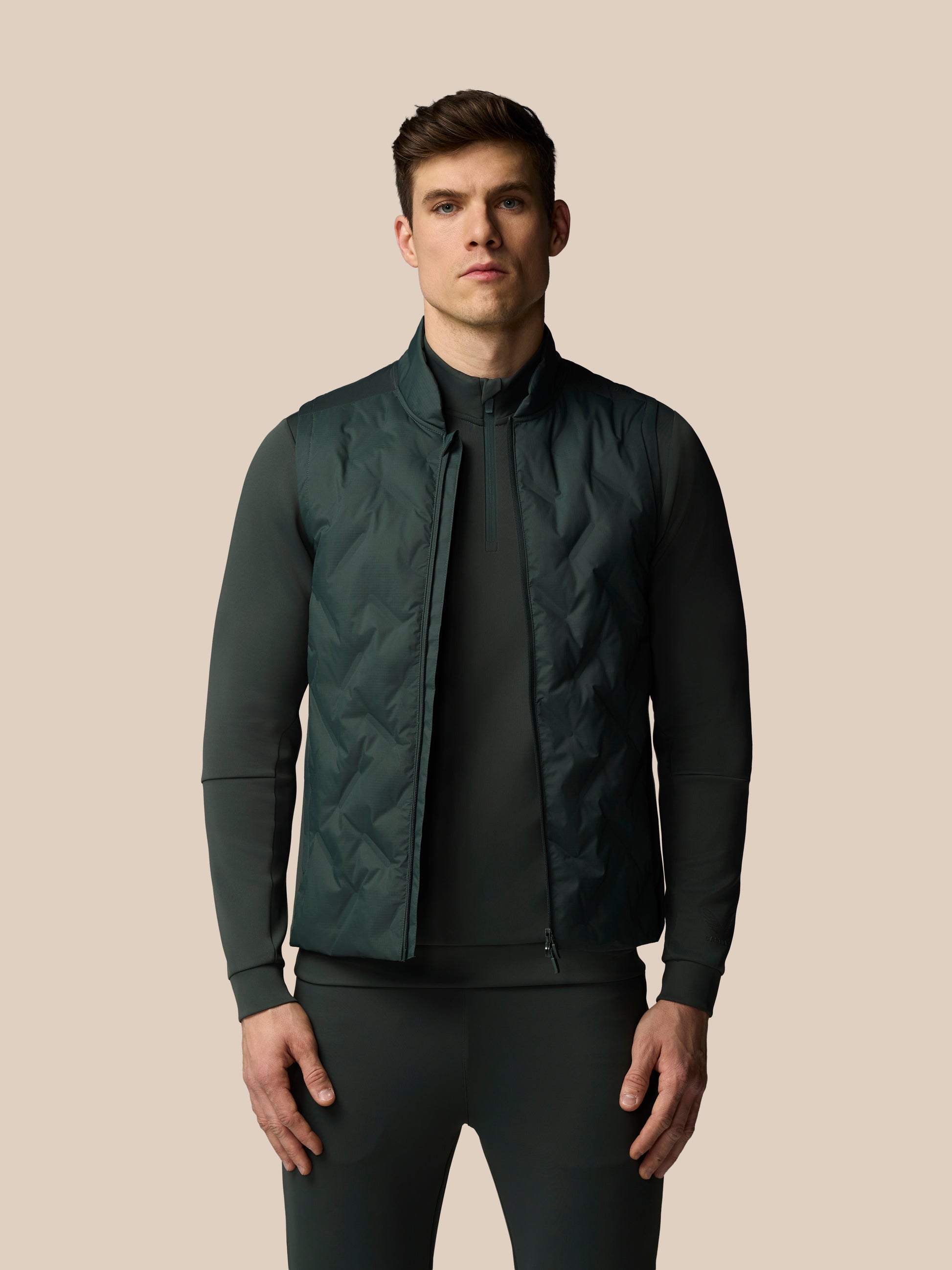 Man wearing a dark green quilted jacket on a beige background