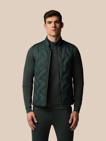 Man wearing a dark green quilted jacket on a beige background