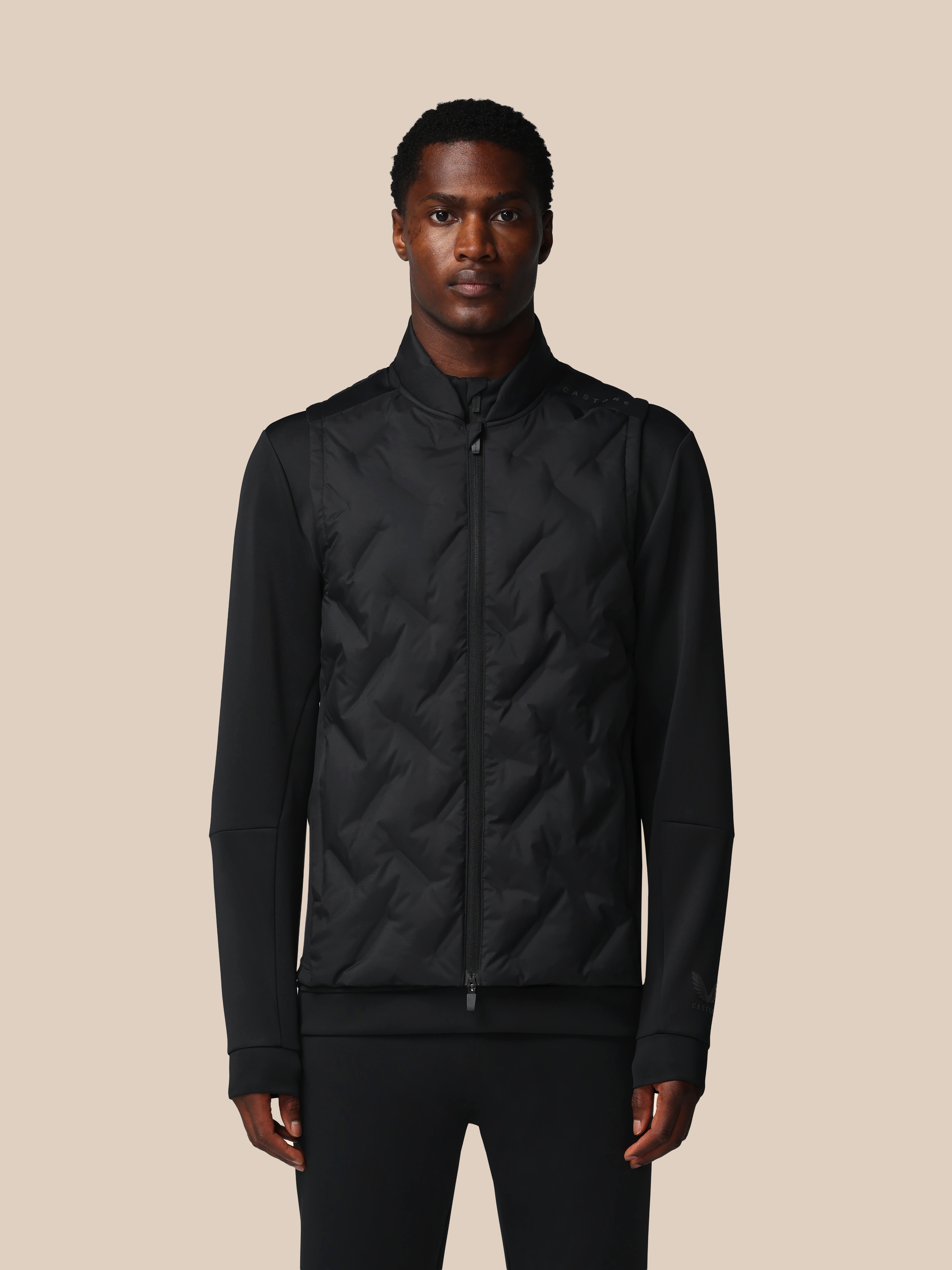 Man wearing a black quilted jacket against a beige background