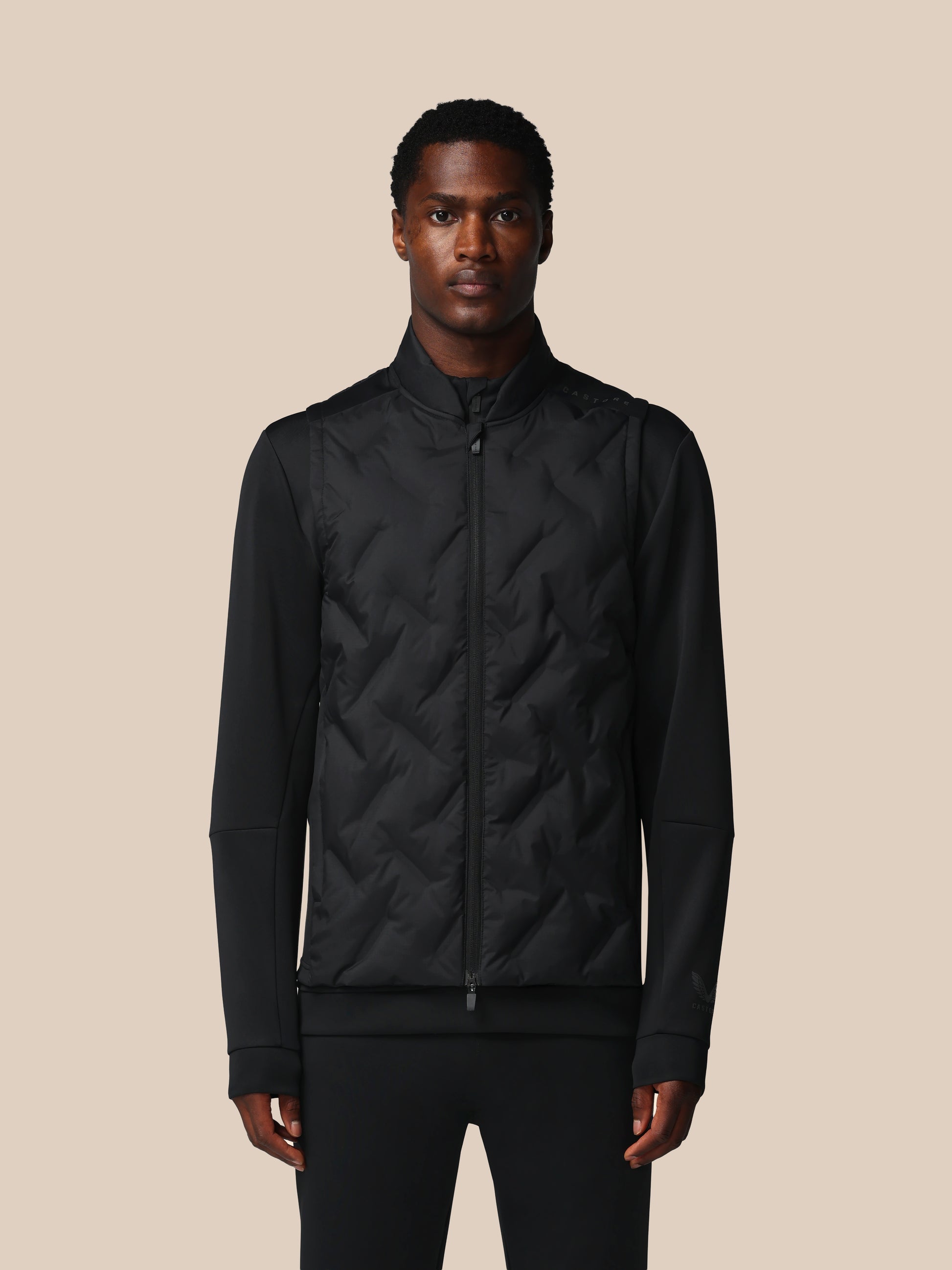 Man wearing a black quilted jacket against a beige background