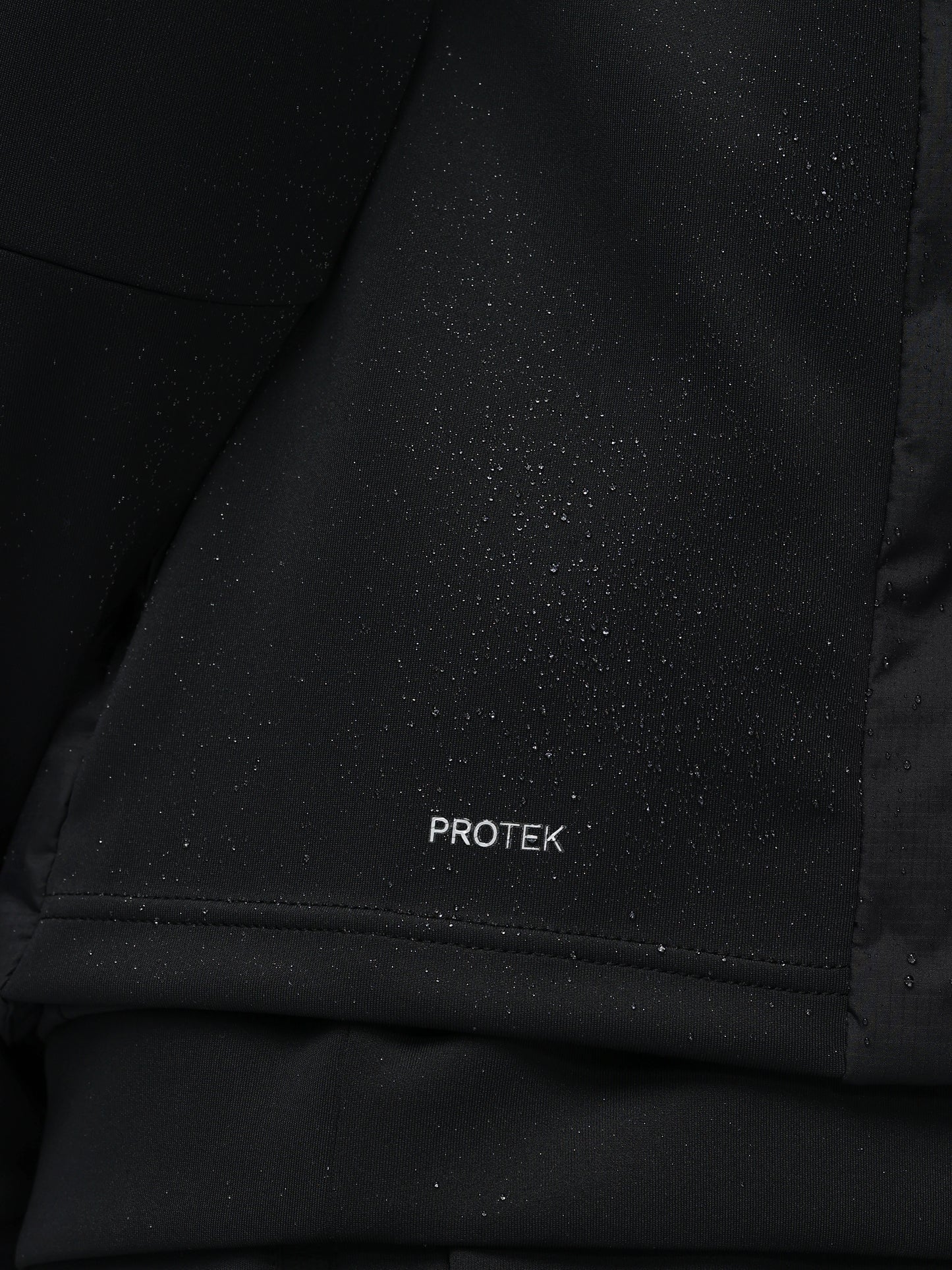 Close-up of a black jacket with 'PROTEK' branding on a dark background