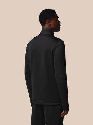 Person wearing a black turtleneck and pants against a beige background