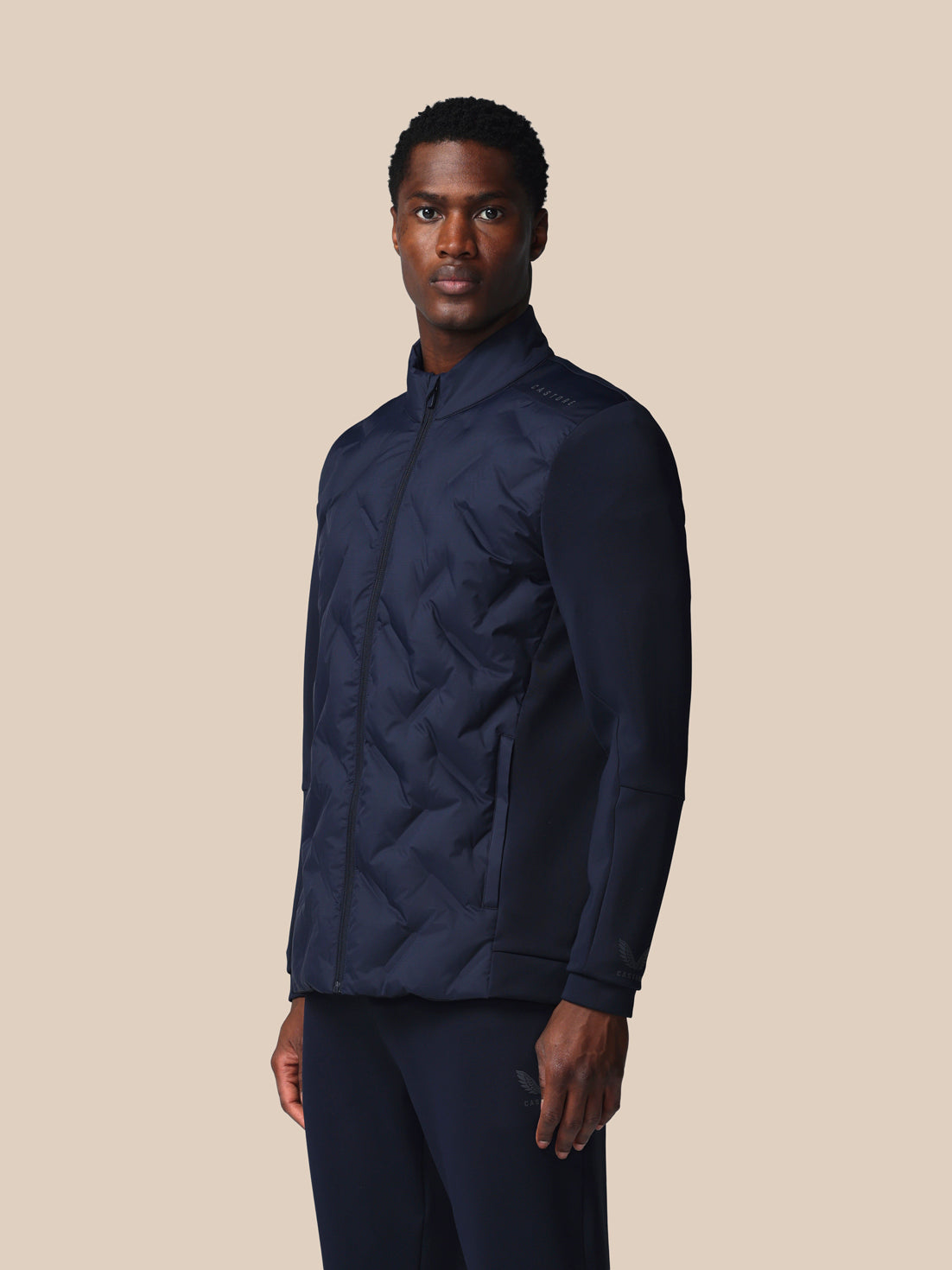 Man wearing a navy quilted jacket on a beige background