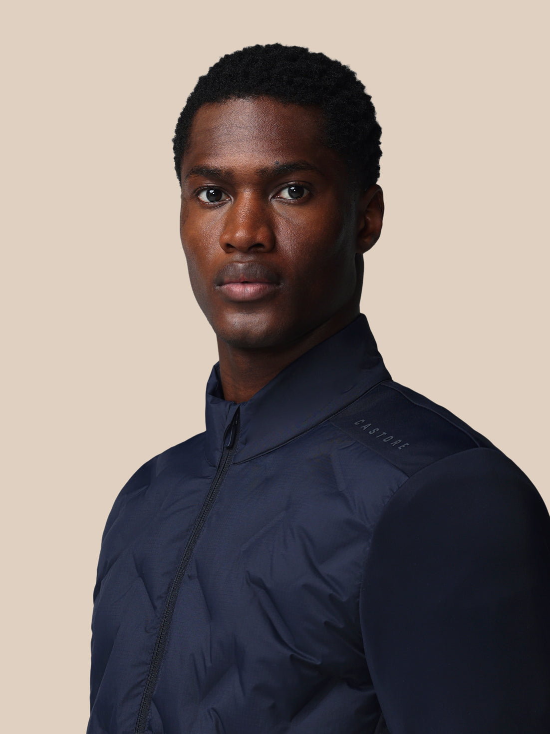 Man wearing a navy blue jacket against a beige background