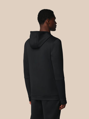 Person wearing a black hoodie from behind on a beige background