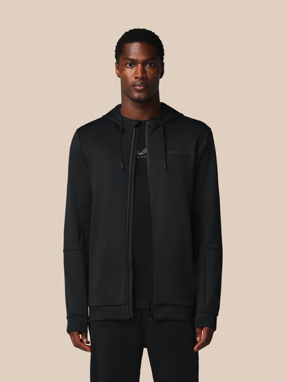 Man wearing a black hoodie with a brand logo on a beige background