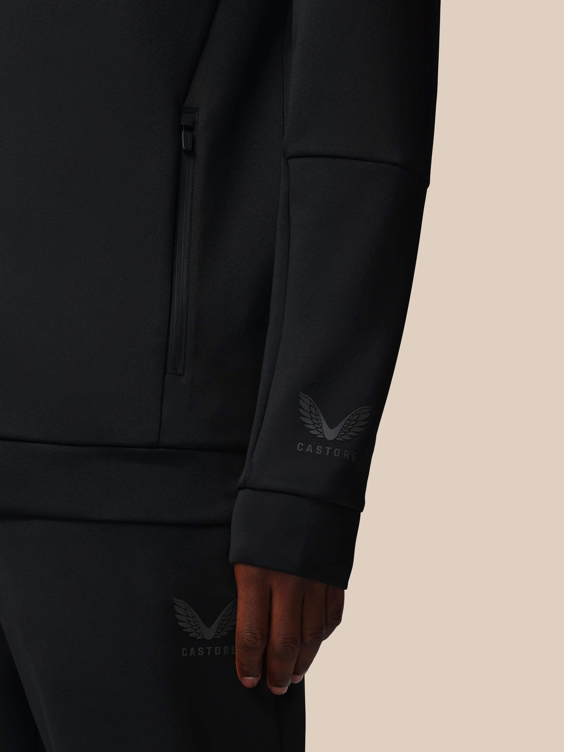 Black jacket with a brand logo on the sleeve against a beige background