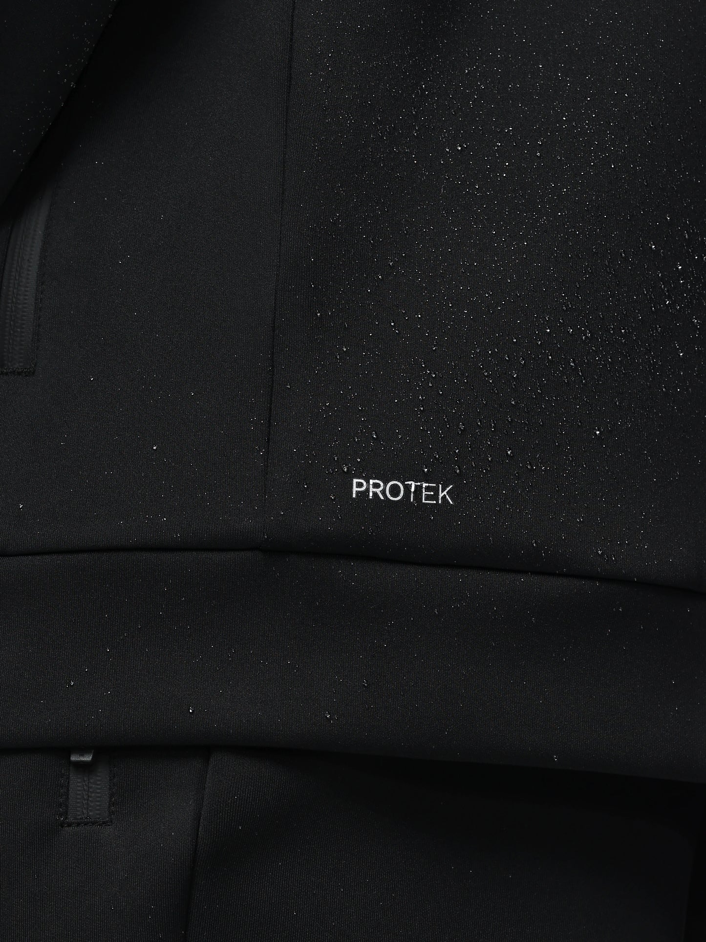 Close-up of a black textured fabric with 'PROTEK' branding.