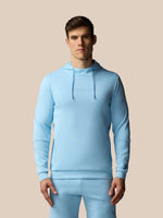 Man wearing a light blue hoodie and pants on a beige background