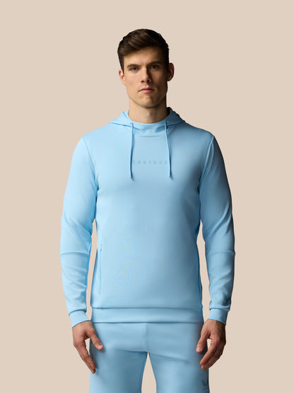 Man wearing a light blue hoodie and pants on a beige background