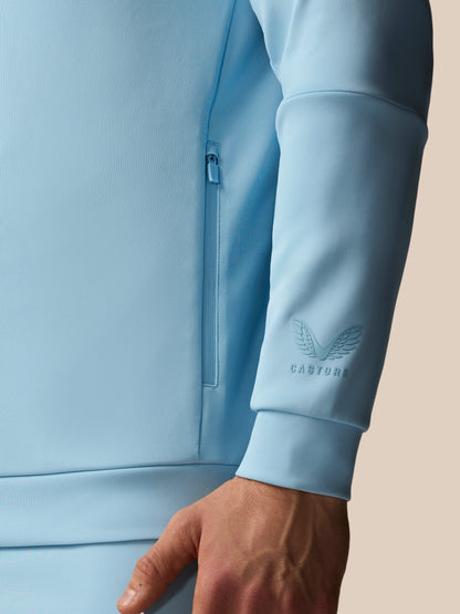 Light blue jacket with a brand logo on the sleeve against a neutral background