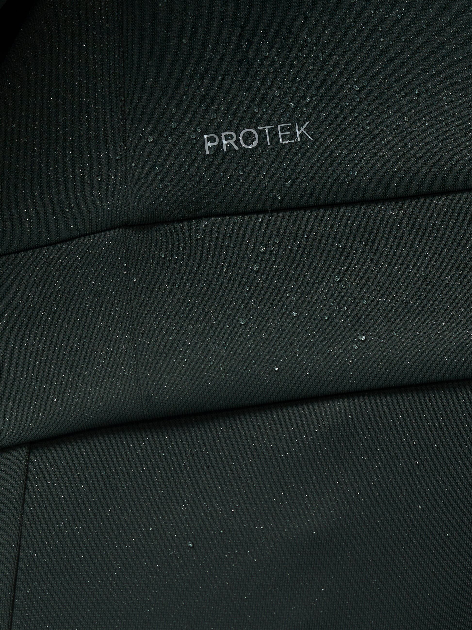 Close-up of a black fabric with 'PROTEK' branding.