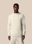 Man wearing a white hoodie and pants on a beige background