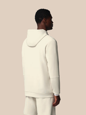 Person wearing a cream-colored hoodie and pants on a beige background
