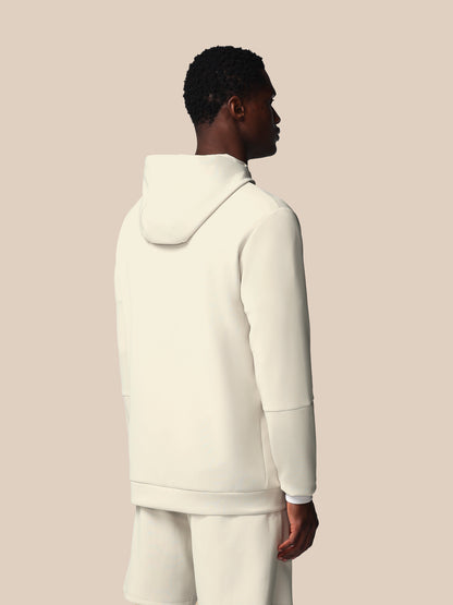 Person wearing a cream-colored hoodie and pants on a beige background