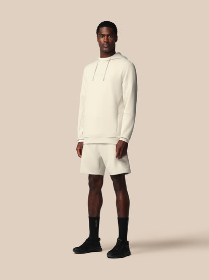 Man wearing a white hoodie and shorts set on a beige background