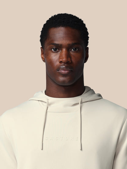 Man wearing a beige hoodie against a plain background