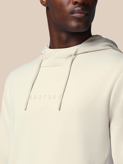 Person wearing a beige hoodie with 'CASTORE' branding on a neutral background