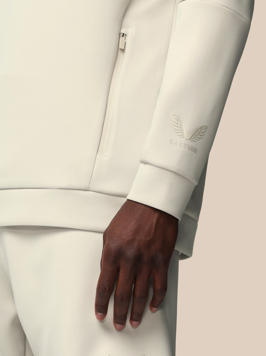 Close-up of a person wearing a light gray suit with a brand logo on the sleeve.