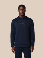 Man wearing a navy hoodie with 'CASTORE' branding on a beige background