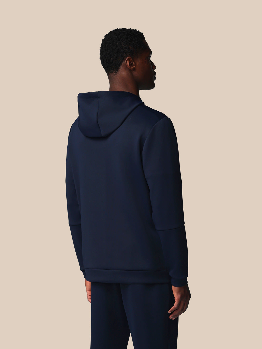 Person wearing a navy blue hoodie on a beige background