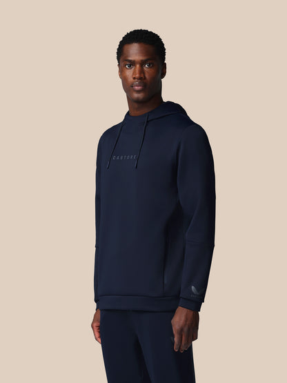 Man wearing a navy hoodie with a brand logo on a beige background