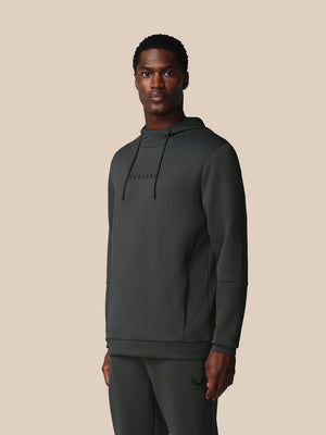Man wearing a dark gray hoodie and pants on a beige background