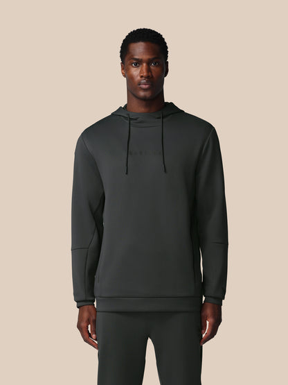 Man wearing a dark green hoodie and pants on a beige background