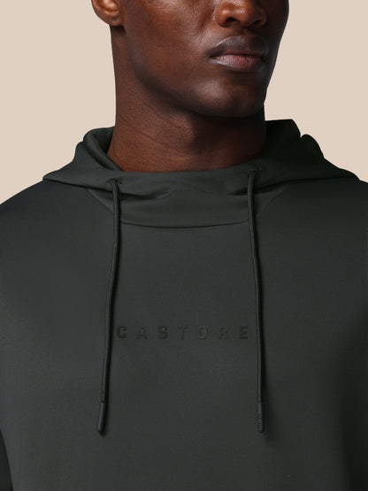 Person wearing a black hoodie with 'CASTORE' branding on a beige background