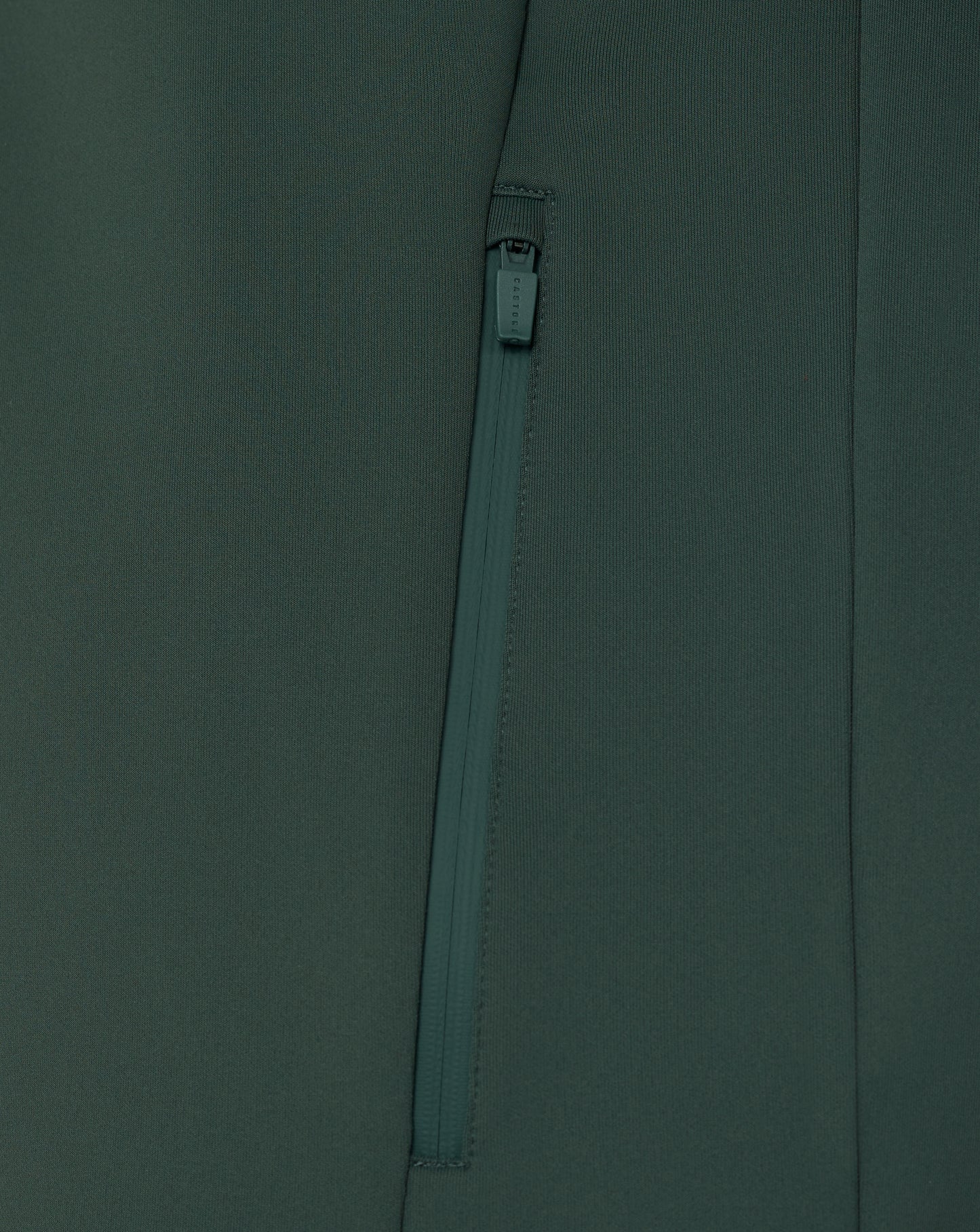 Close-up of a zipper on a dark green fabric background
