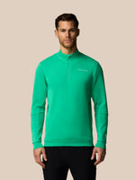 Man wearing a green sweatshirt with a brand logo on a beige background