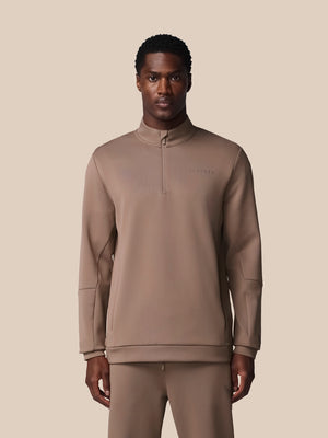 Man wearing a brown tracksuit against a beige background