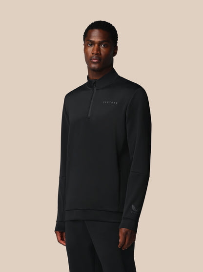 Man wearing a black quarter-zip sweatshirt on a beige background