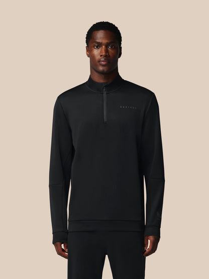 Man wearing a black quarter-zip sweatshirt on a beige background