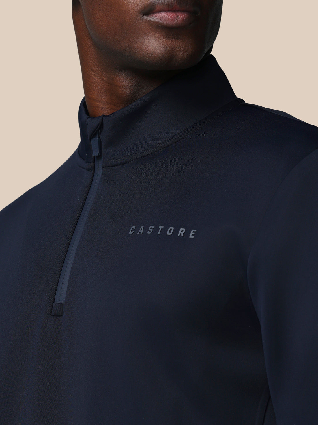 Person wearing a black hoodie with 'CASTORE' branding on a beige background