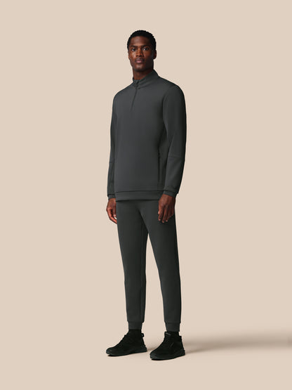 Man wearing a dark gray tracksuit on a beige background
