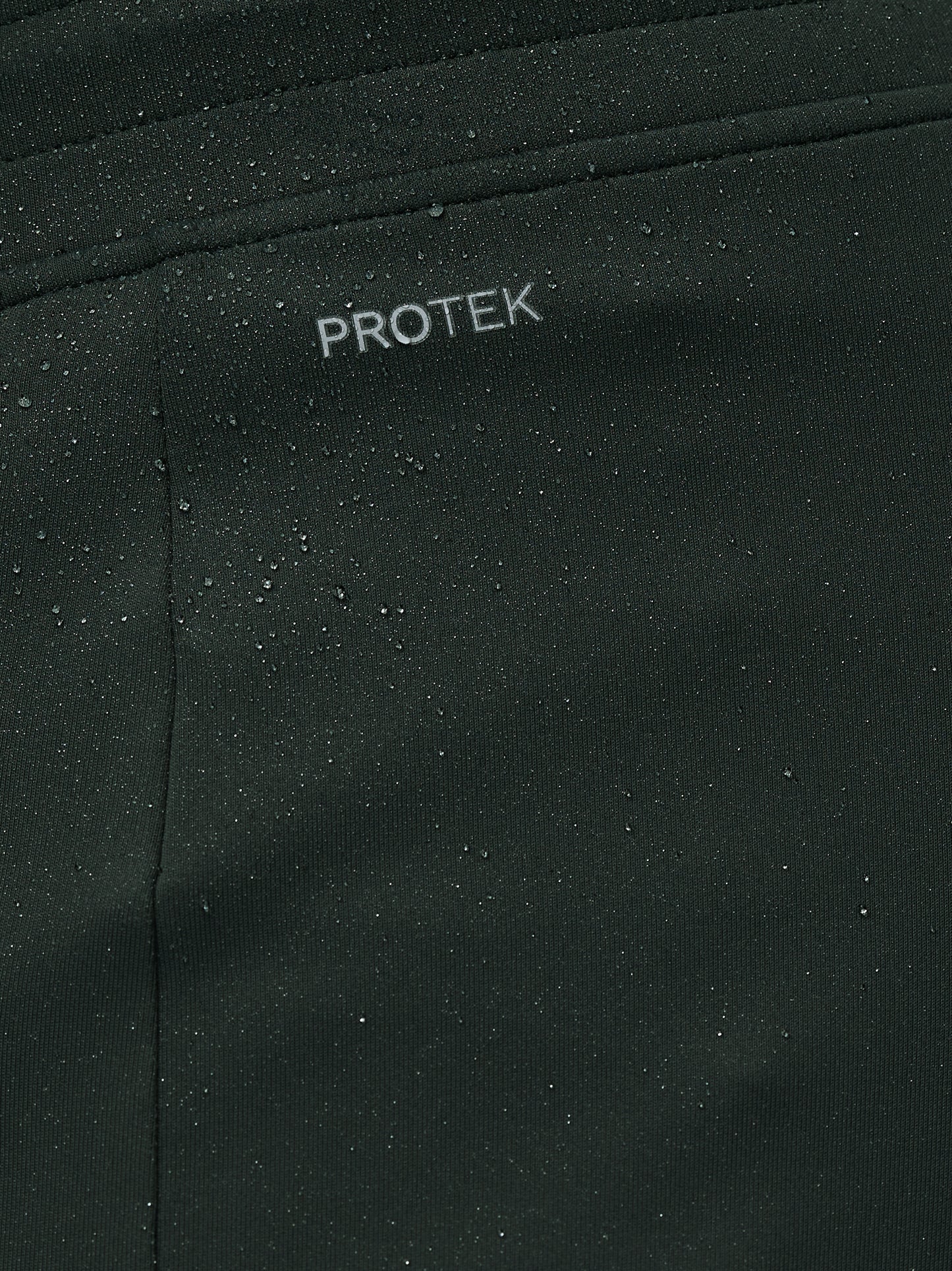 Close-up of black fabric with 'PROTEK' branding.
