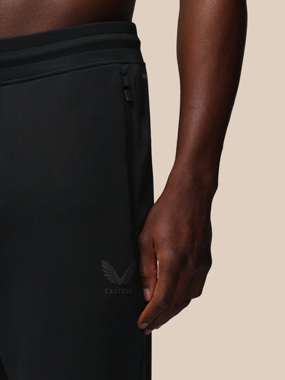Black athletic pants with a brand logo on a beige background