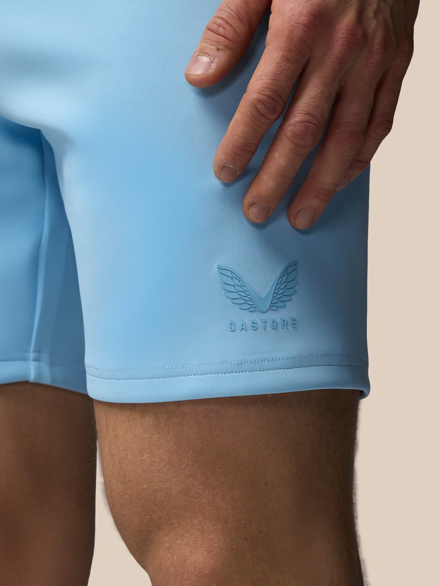Light blue athletic shorts with a brand logo on a beige background