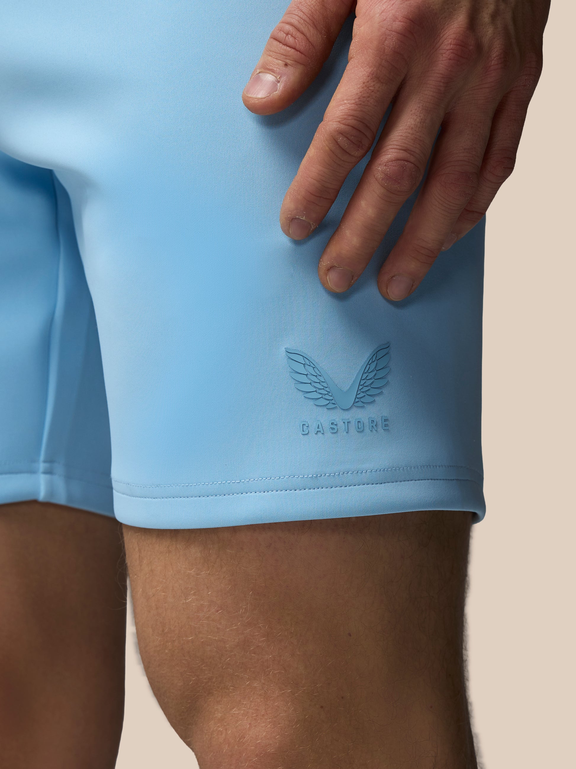 Light blue athletic shorts with a brand logo on a beige background